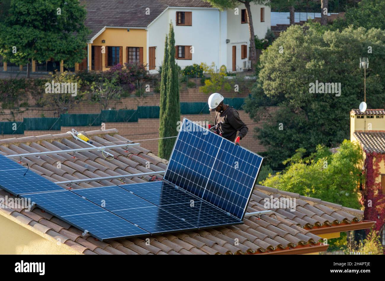 Elektrovertragsarbeiter von HolaLuz installieren Solarzellen auf dem Dach eines Wohnhauses während des Aufbaus eines subventionierten Stromversorgungssystems für Privathäuser nördlich von Barcelona in Carbils, Katalonien, Spanien. © Olli Geibel Stockfoto