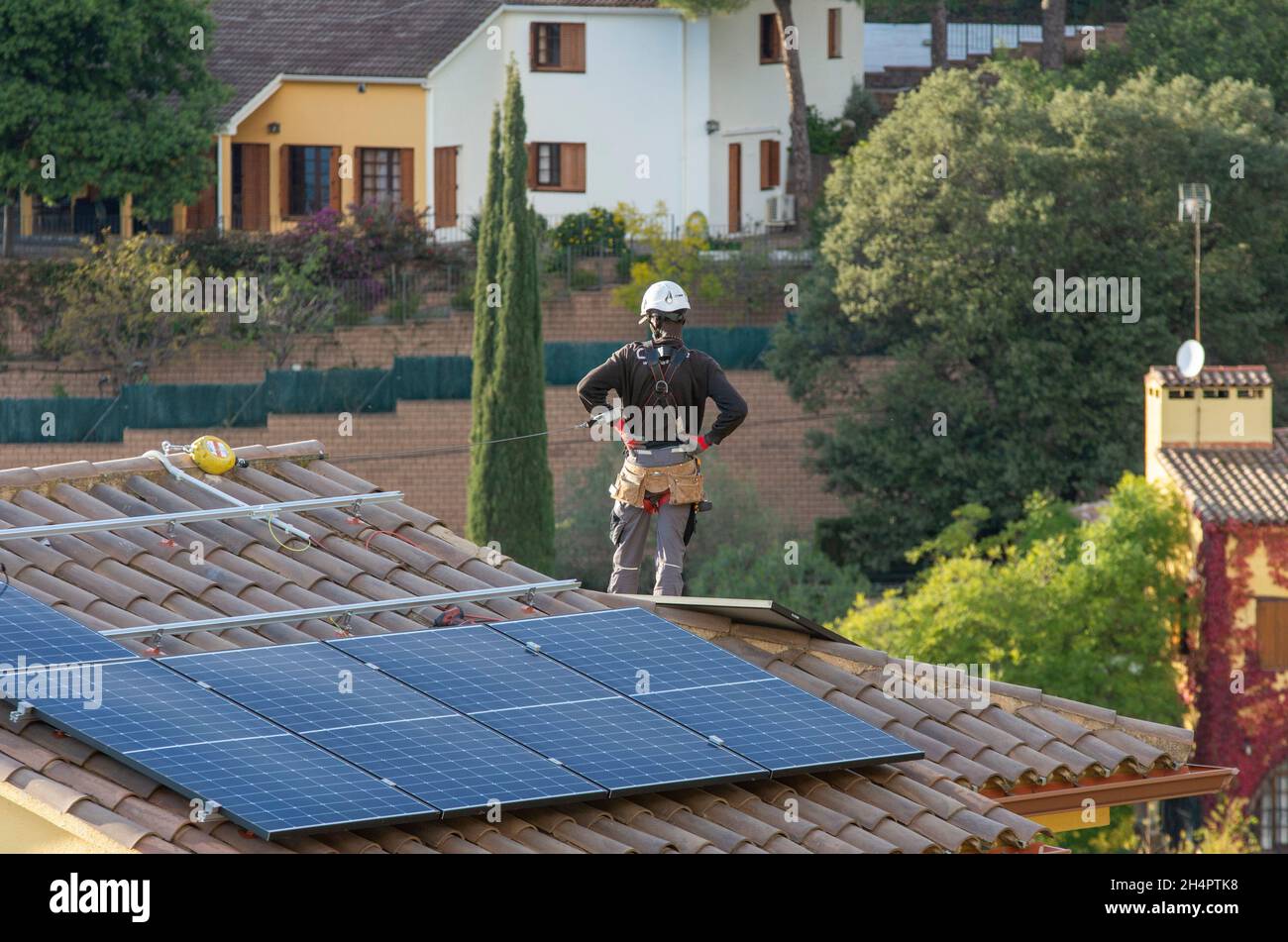 Elektrovertragsarbeiter von HolaLuz installieren Solarzellen auf dem Dach eines Wohnhauses während des Aufbaus eines subventionierten Stromversorgungssystems für Privathäuser nördlich von Barcelona in Carbils, Katalonien, Spanien. © Olli Geibel Stockfoto