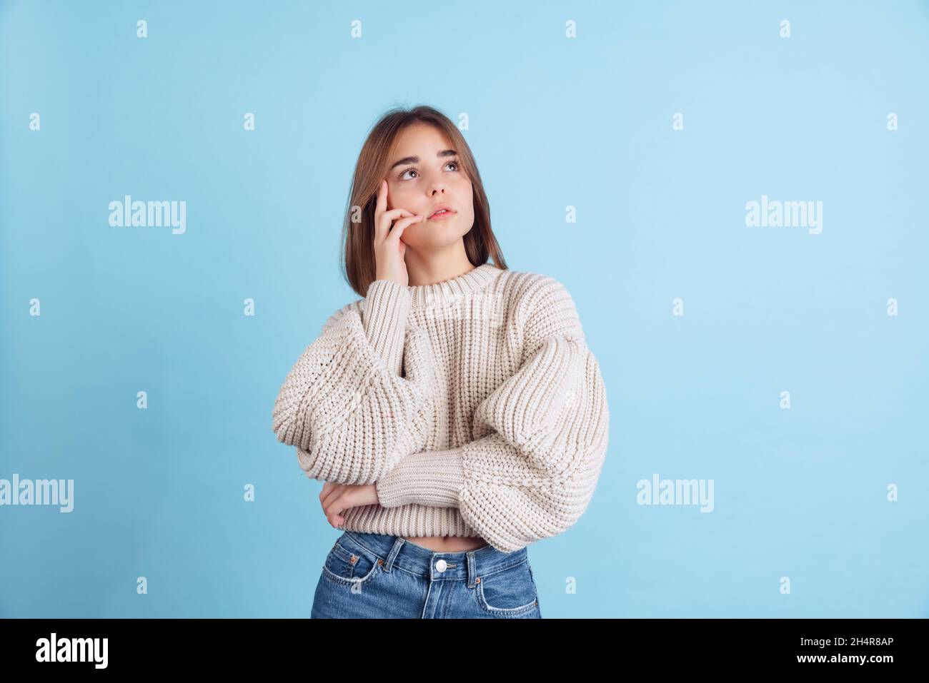 Portrait eines jungen schönen Mädchens, Student in legerer Kleidung, isoliert auf hellblauem Studiohintergrund aufblickend Stockfoto