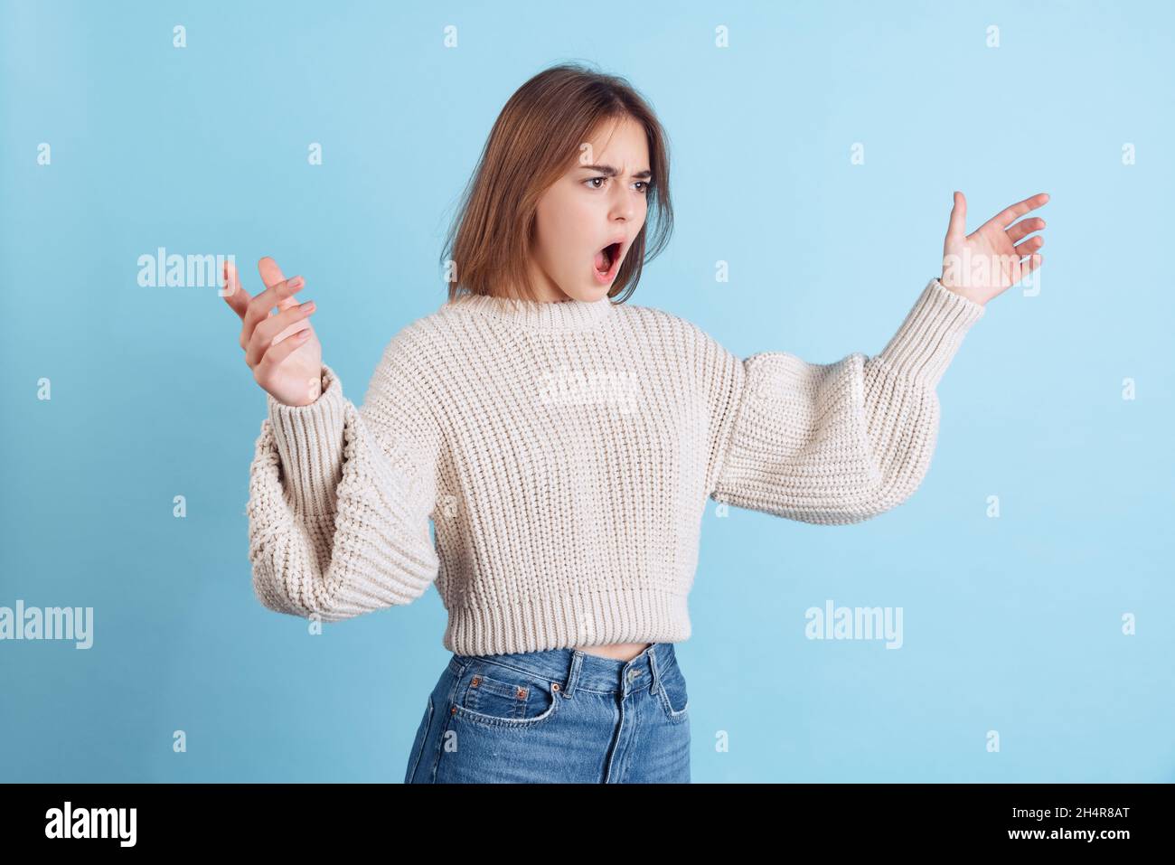 Dynamisches Bild von jungen beuatiful Mädchen, Student in Freizeitkleidung öffnet ihren Mund in Überraschung isoliert auf hellblauem Studio-Hintergrund. Stockfoto
