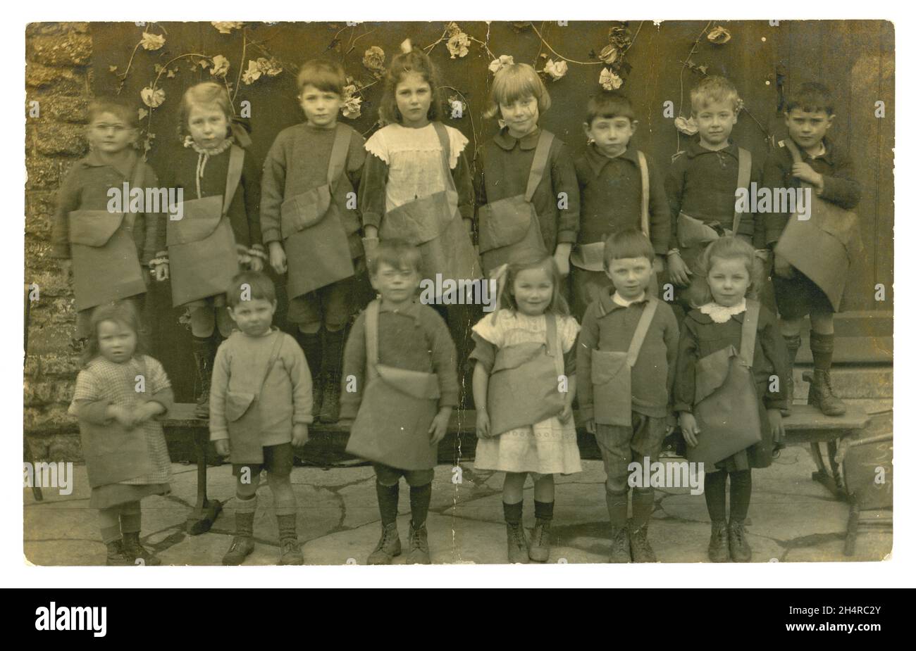 Originell charmant und klar, edwardianische Postkarte mit einer Gruppe kleiner Schulkinder, die ihre Umhängetaschen bei einer Maitagsparade in Norwich tragen. Viele kleine Charaktere. Die Postkarte ist vom Mai 1. 1906. Norwich, Norfolk, England, Großbritannien Stockfoto