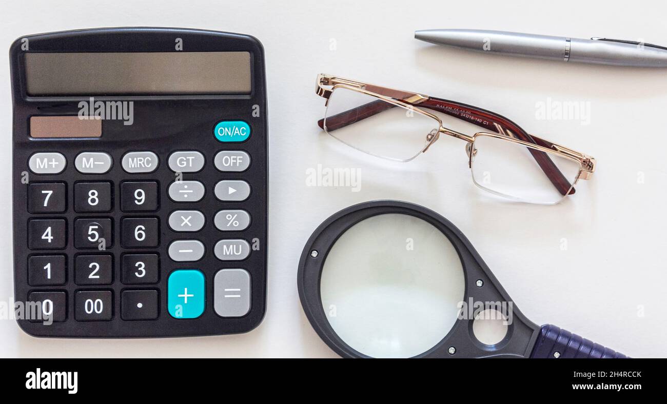Business-Zubehör Lupe, Taschenrechner, Stift, Notizblock, Brille auf weißem Hintergrund. Stockfoto