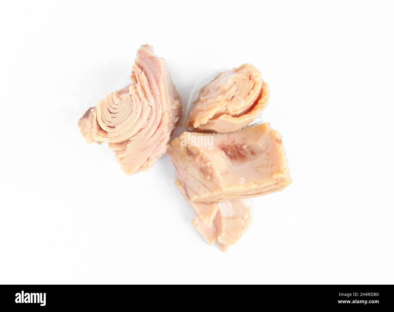 Thunfisch-Stücke auf weißem Hintergrund isoliert. Konserviertes und zubereitetes Fischfleisch Stockfoto