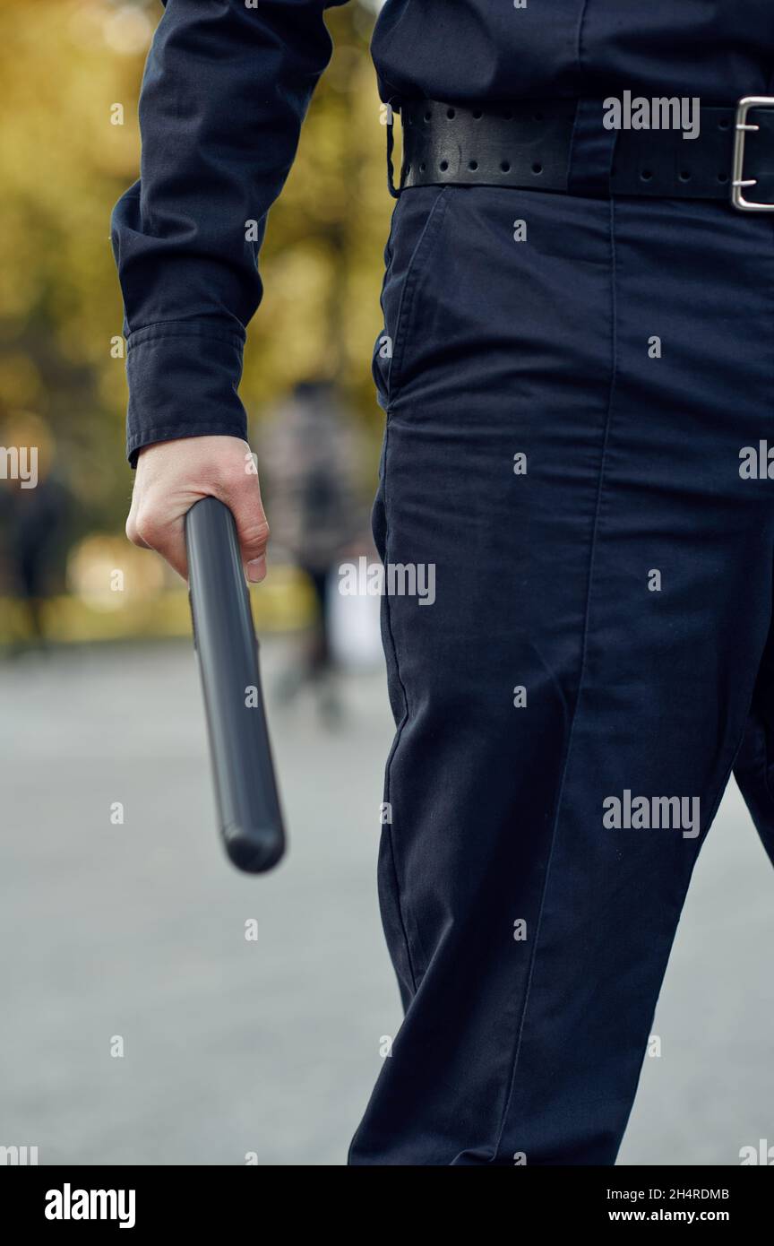 Ein Polizist in Uniform hält den Stab Stockfoto