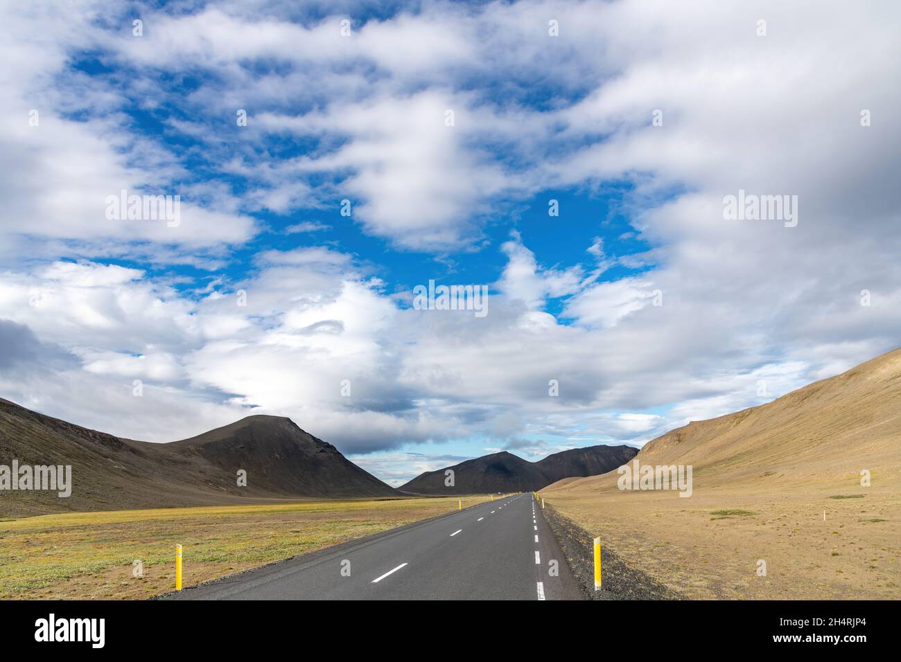 Panoramablick über eine zweispurige Straße auf Island, durch das karge isländische Hochland mit Vulkanen und Bergen im Norden des Landes Stockfoto
