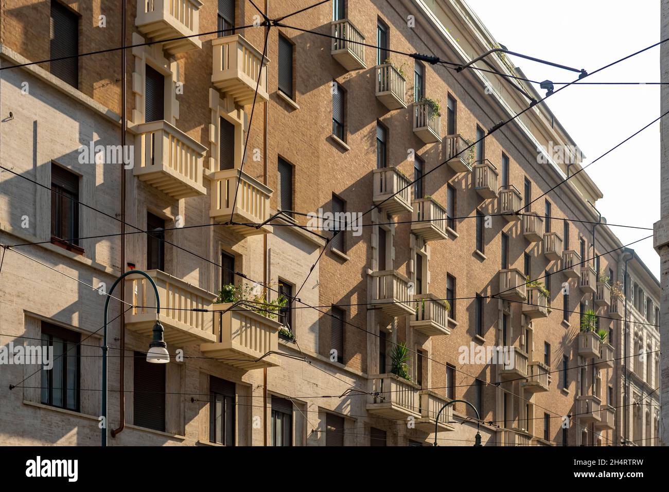 Wohngebäude aus dem 20. Jahrhundert mit Straßenbahnkabeln bei Sonnenuntergang, Turin, Italien. Stockfoto