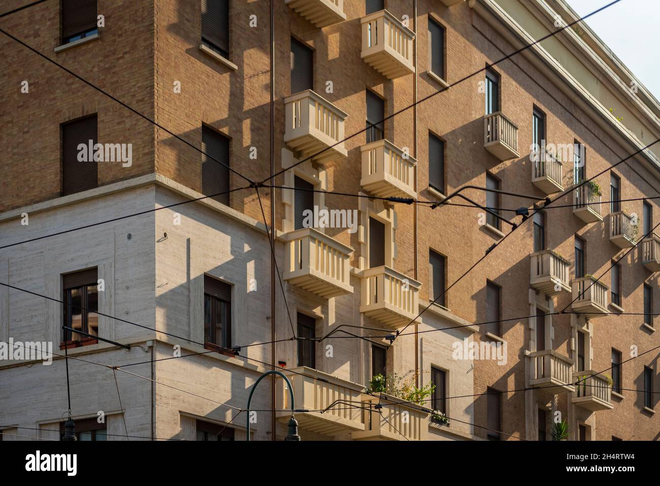 Wohngebäude aus dem 20. Jahrhundert mit Straßenbahnkabeln bei Sonnenuntergang, Turin, Italien. Stockfoto