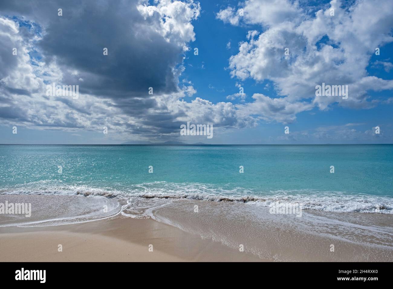 Seascape mit Sandstrand, azurblauem Wasser, weißen Wolken und der Insel Montserrat von Antigua, den Kleinen Antillen im Karibischen Meer aus gesehen Stockfoto