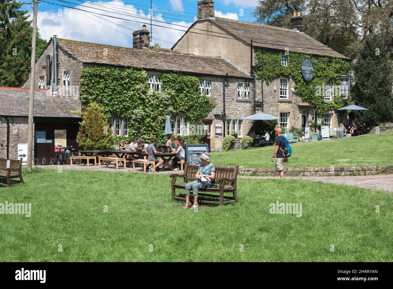 Pub Yorkshire, Blick im Sommer auf Menschen, die vor dem Lister Arms sitzen, einem beliebten historischen Gasthaus im Zentrum von Malham Village, Yorkshire Dales, Großbritannien Stockfoto