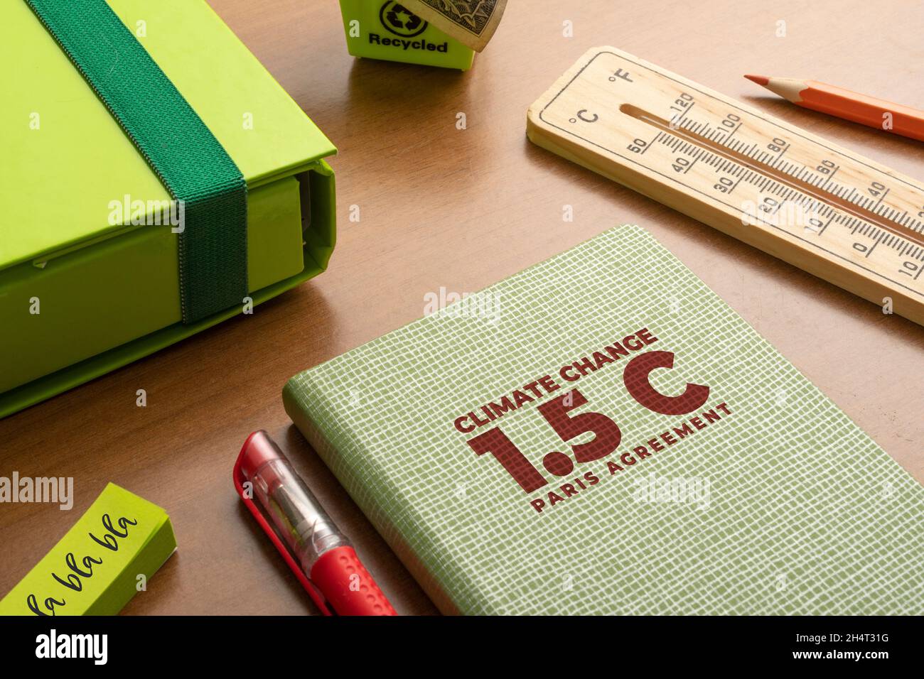 1.5 Grad Pariser Abkommen Konzept: Verschiedene grüne Objekte und ein Thermometer auf einem Holztisch. Stockfoto