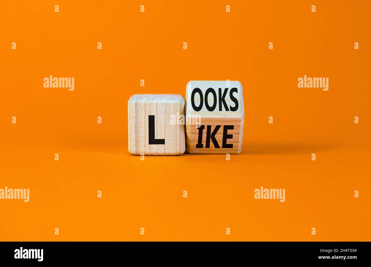 Sieht aus wie ein Symbol. Gedreht wurde ein Holzwürfel mit den Worten „sieht aus wie“. Schöner orangefarbener Hintergrund. Business, beliebte Zitate und sieht aus wie Konzept. Kopie sp Stockfoto