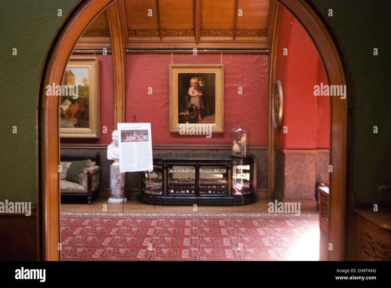 Blick durch den Torbogen auf Gemälde und Vitrine in Cragside, Rothbury, Northumberland, England, Großbritannien, Vereinigtes Königreich Stockfoto