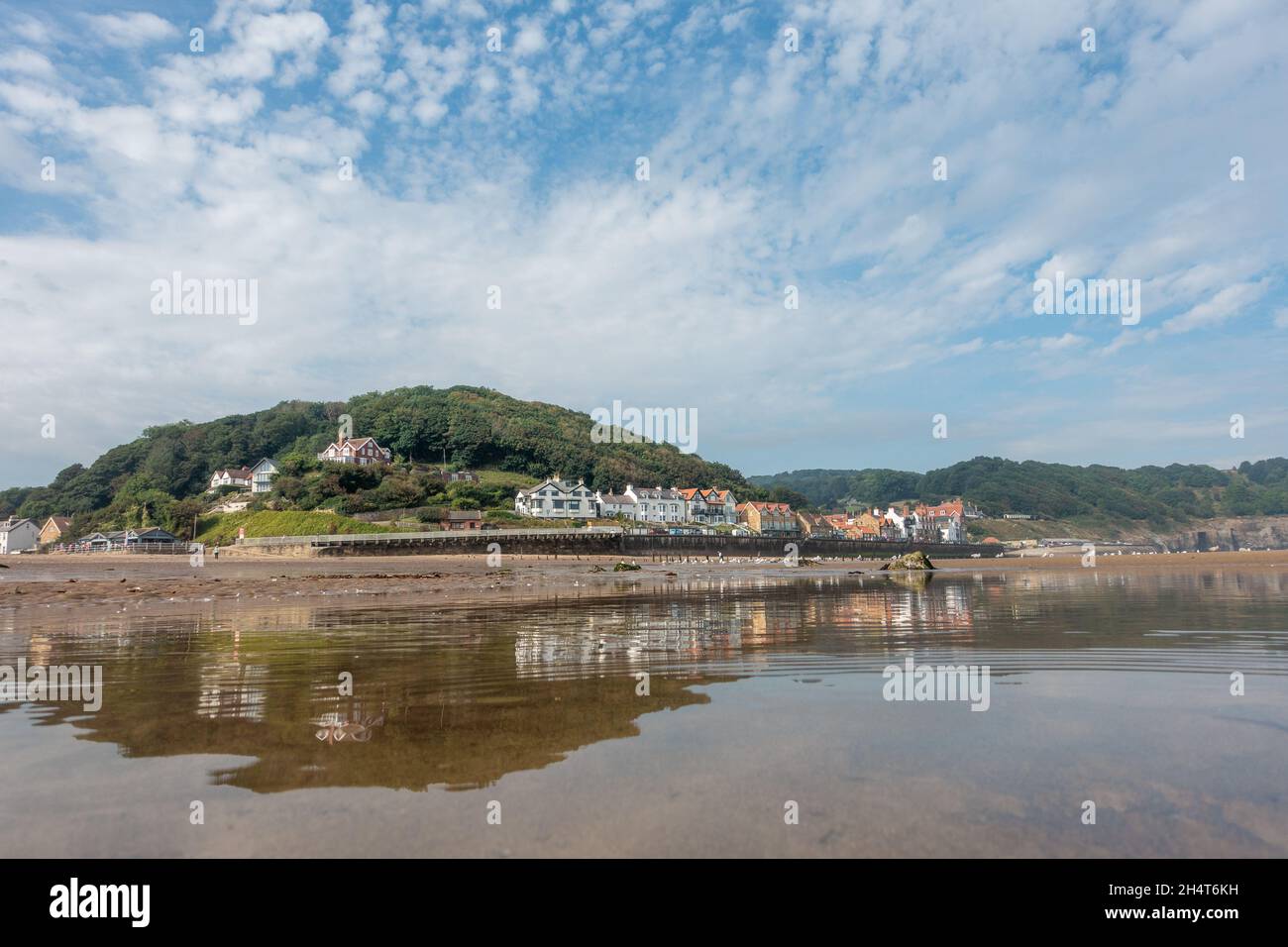 Der hundefreundliche Strand Sandsend ist der perfekte Ort für einen Spaziergang am Strand entlang, hier an einem schönen sonnigen Tag mit einer atemberaubenden Spiegelung im tiefen Meer Stockfoto