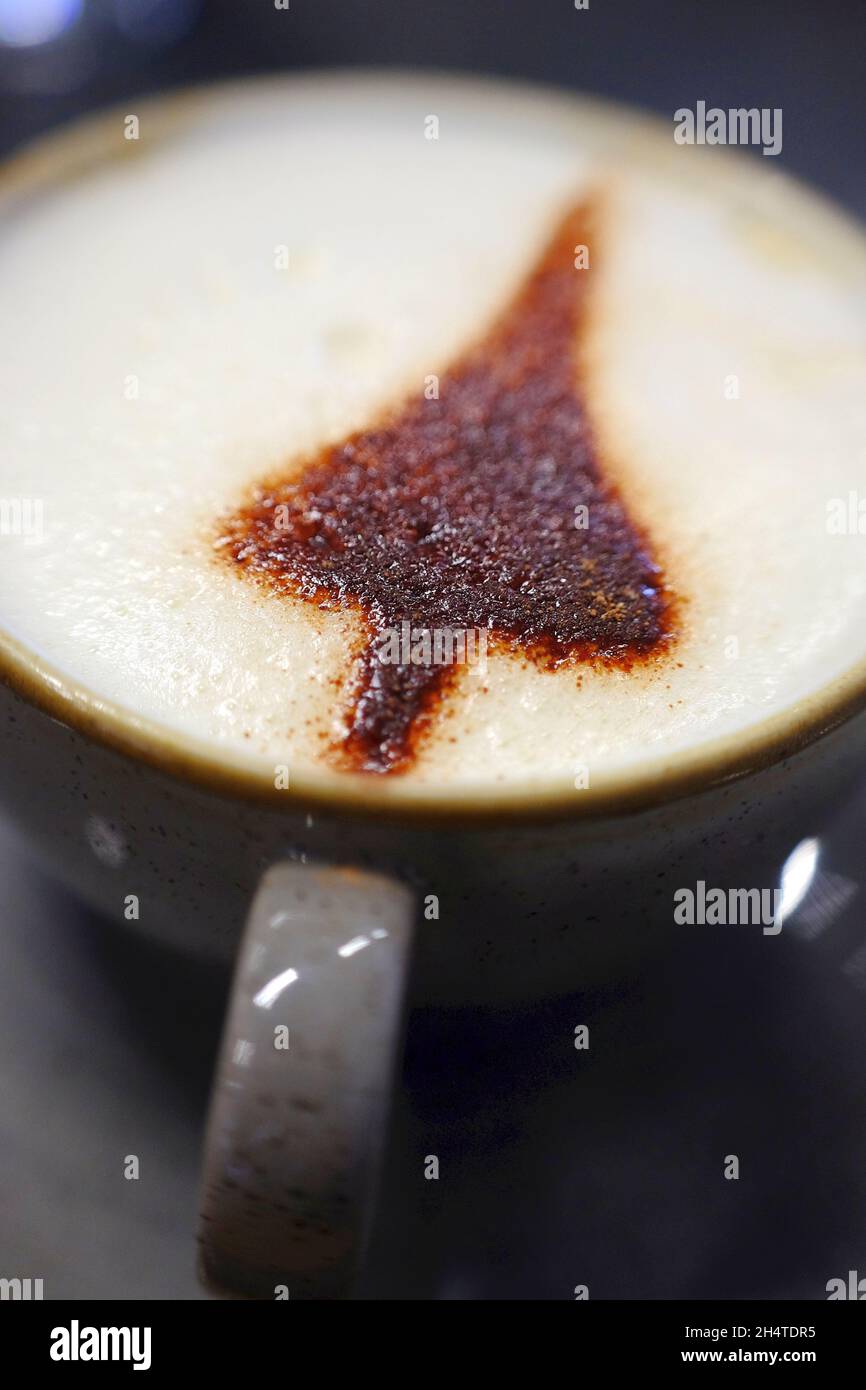 Ein Kaffeebecher Cappuccino mit einem Concorde-Schatten in Schokoladenstreuseln. Stockfoto