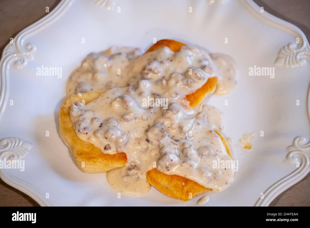 Auf einem weißen Teller mit einer gewürfelten Milchgravie mit Schweinewurst über Keksen. Stockfoto