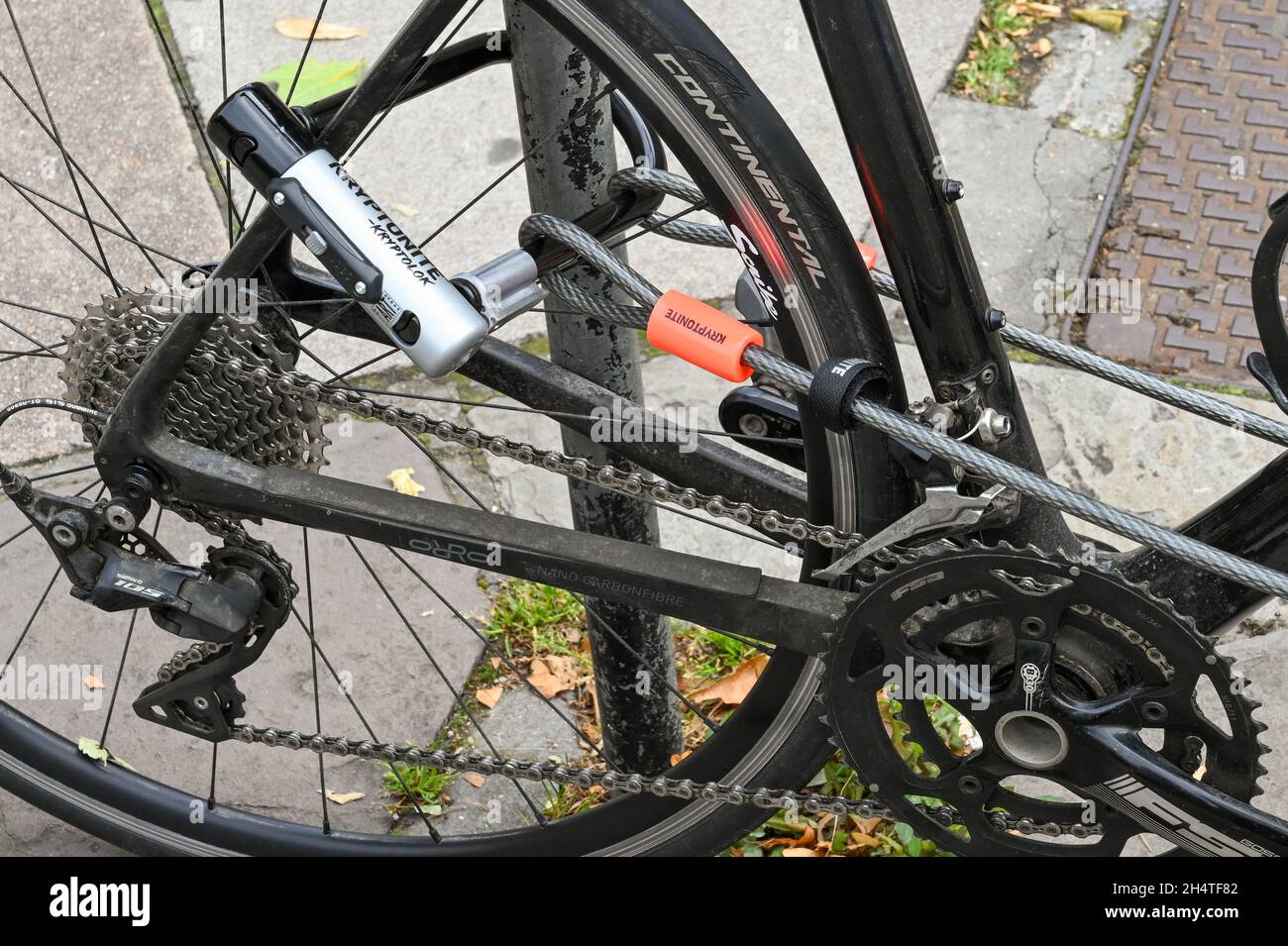 Bath, England - August 2021: Nahaufnahme eines Stahlseiles und eines Schlosses, das einen Fahrradrahmen an einem Fahrradträger befestigt Stockfoto