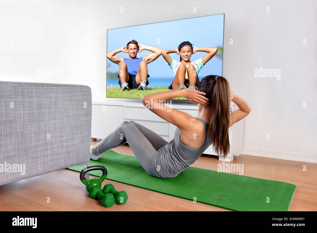 Heimfitness-Konzept. Frau beim Krafttraining abs situps Bodyweight Boden Übungen beobachten ein dvd-Training oder Web-Videos auf einem Smart-tv im Stockfoto