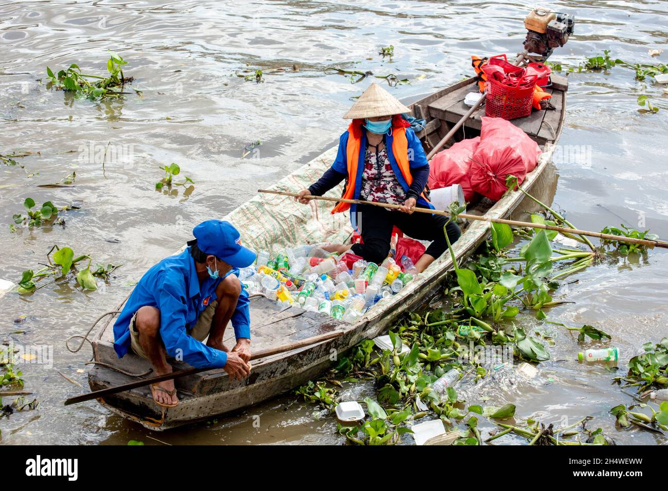 Arme Arbeiter nehmen Plastikflaschen auf, die die Umwelt am Fluss in Vietnam verschmutzen Stockfoto