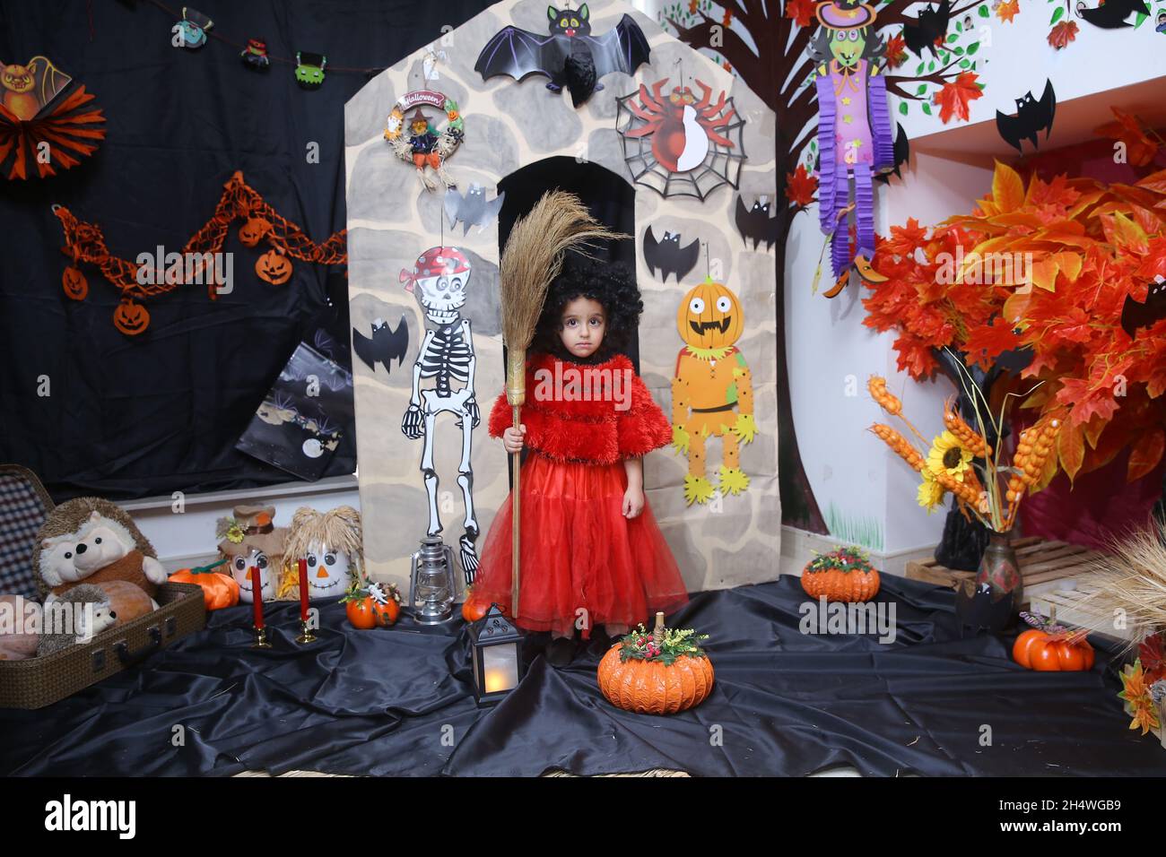Aserbaidschan Baku . 01.11.2021 . Ein Mädchen in Form einer Hexe auf einem Besenstiel posiert vor dem Hintergrund von Kürbissen in den Halloween-Ferien. Mädchen Stockfoto