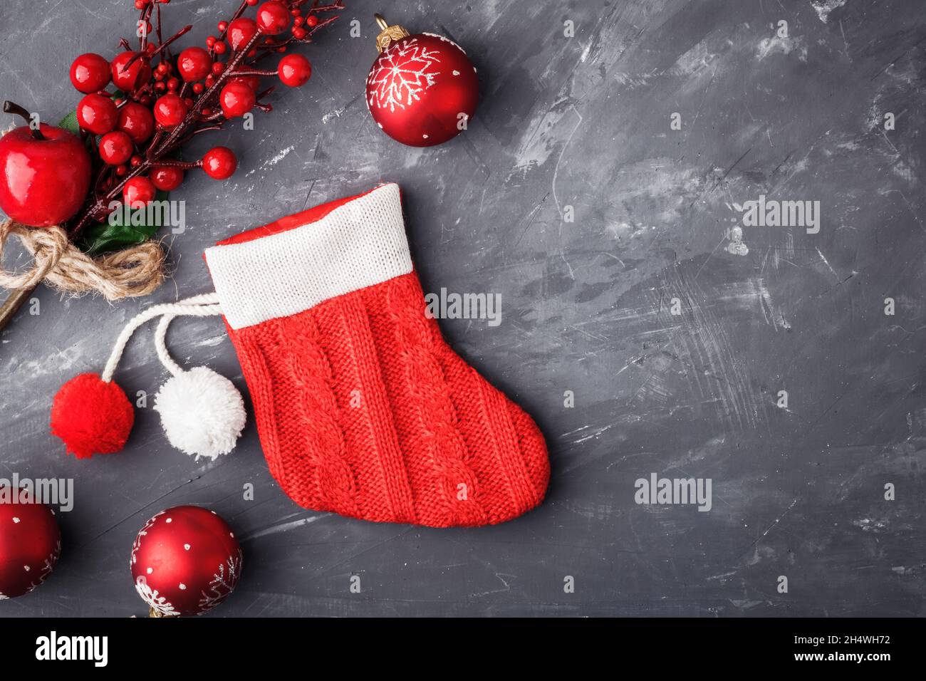 Roter Weihnachtsstiefel-Strumpf der Weihnachtsmann in der Nähe von Weihnachtsdekorationen auf blauem Beton-Hintergrund. Abstrakter Weihnachtshintergrund. Speicherplatz kopieren Stockfoto