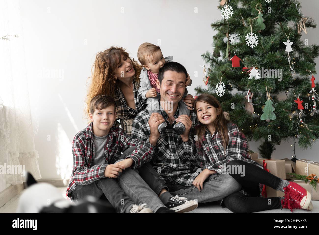 Porträt einer großen vollkaukasischen Familie mit drei Kindern zu Weihnachten mit Geschenken auf dem Boden des Hauses im Wohnzimmer sitzen. Stockfoto