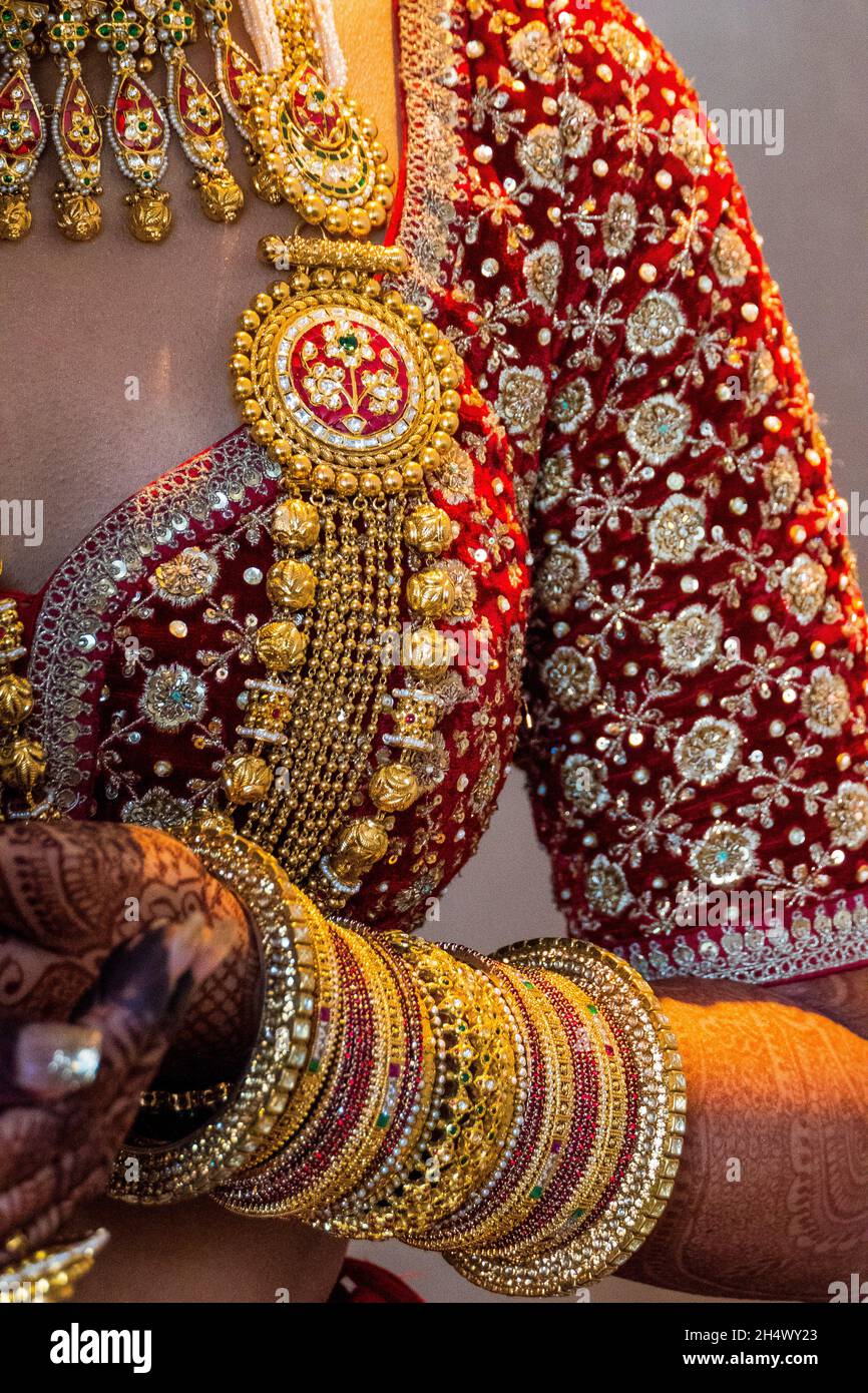 Vertikale Aufnahme einer indischen Braut in einem traditionellen Hochzeitskleid und Schmuck mit Henna an den Händen Stockfoto