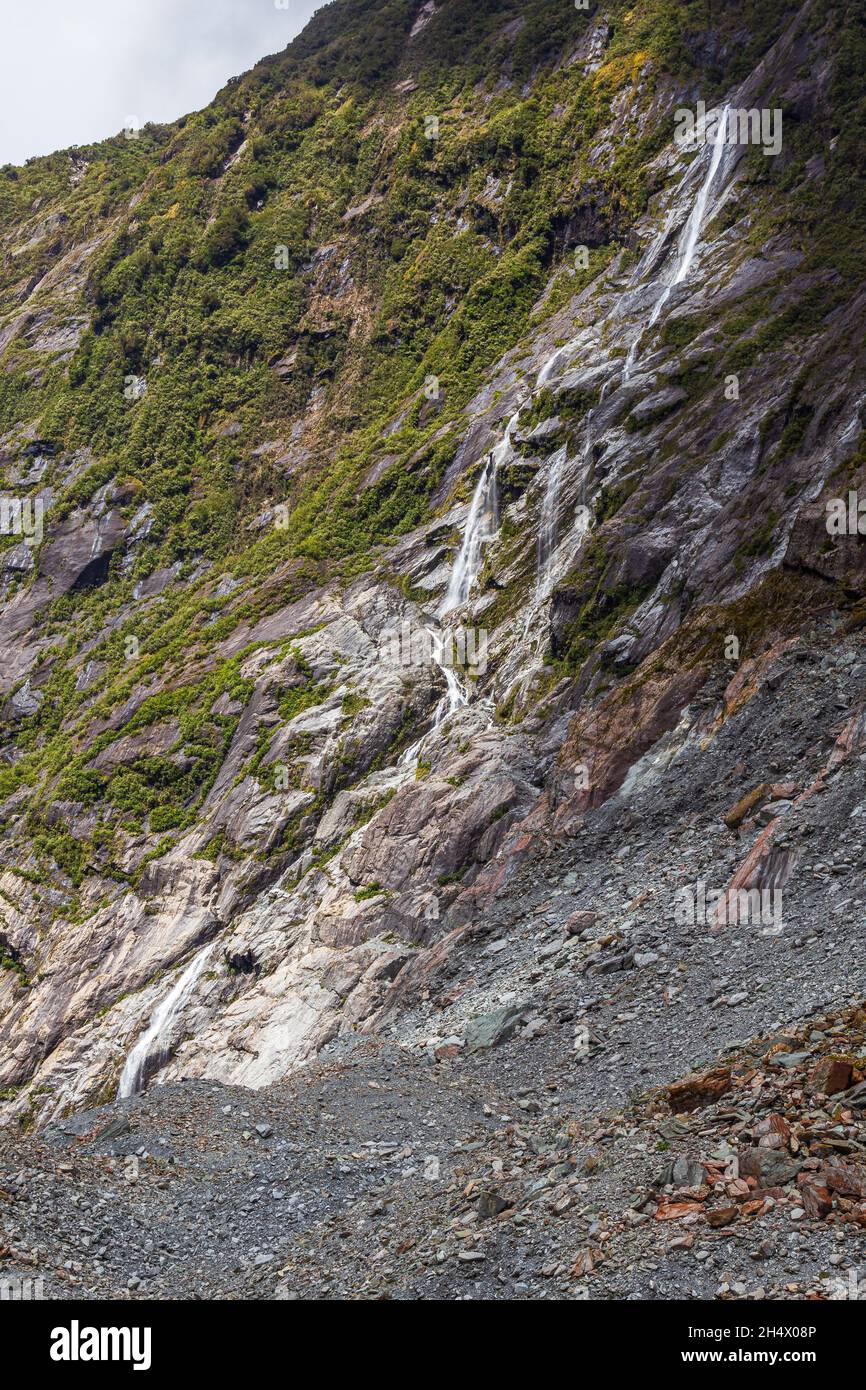 Steine und kleiner Wasserfall. Franz-Joseph-Gletscher. Südinsel, Neuseeland Stockfoto