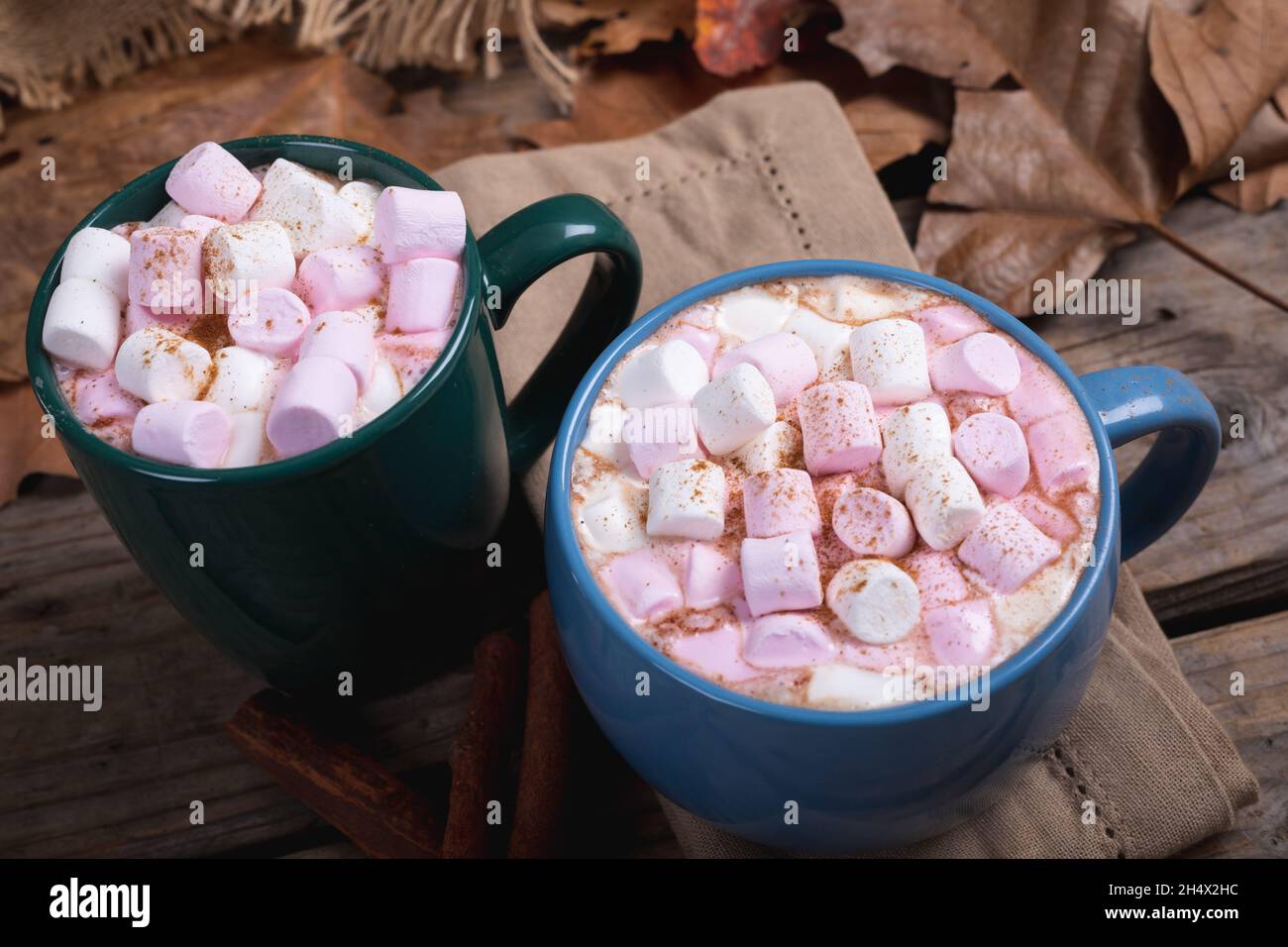 Rosafarbene und weiße Marshallows mit heißem Schokoladengetränk, gefüllt in Tassen auf dem Tisch im Café Stockfoto