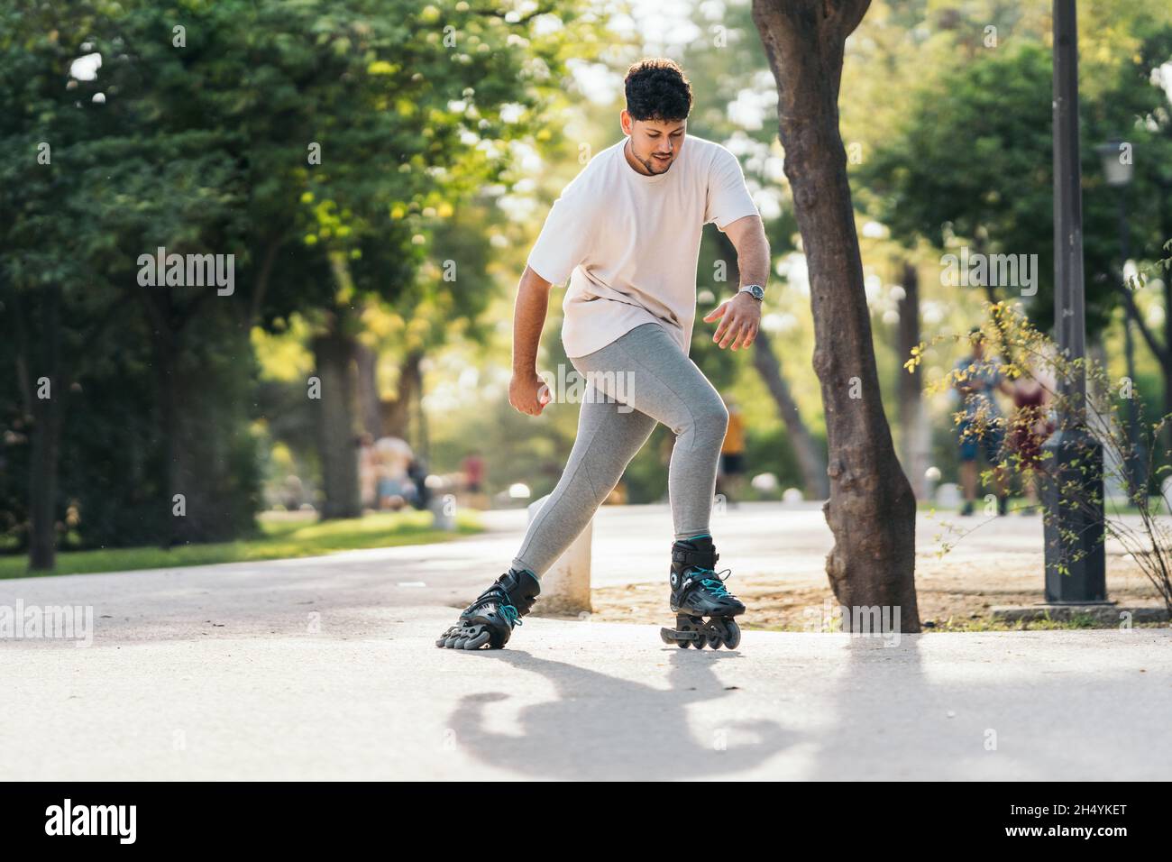 Man Skating mit Inline-Skates auf einem gepflasterten Pfad eines Parks Stockfoto