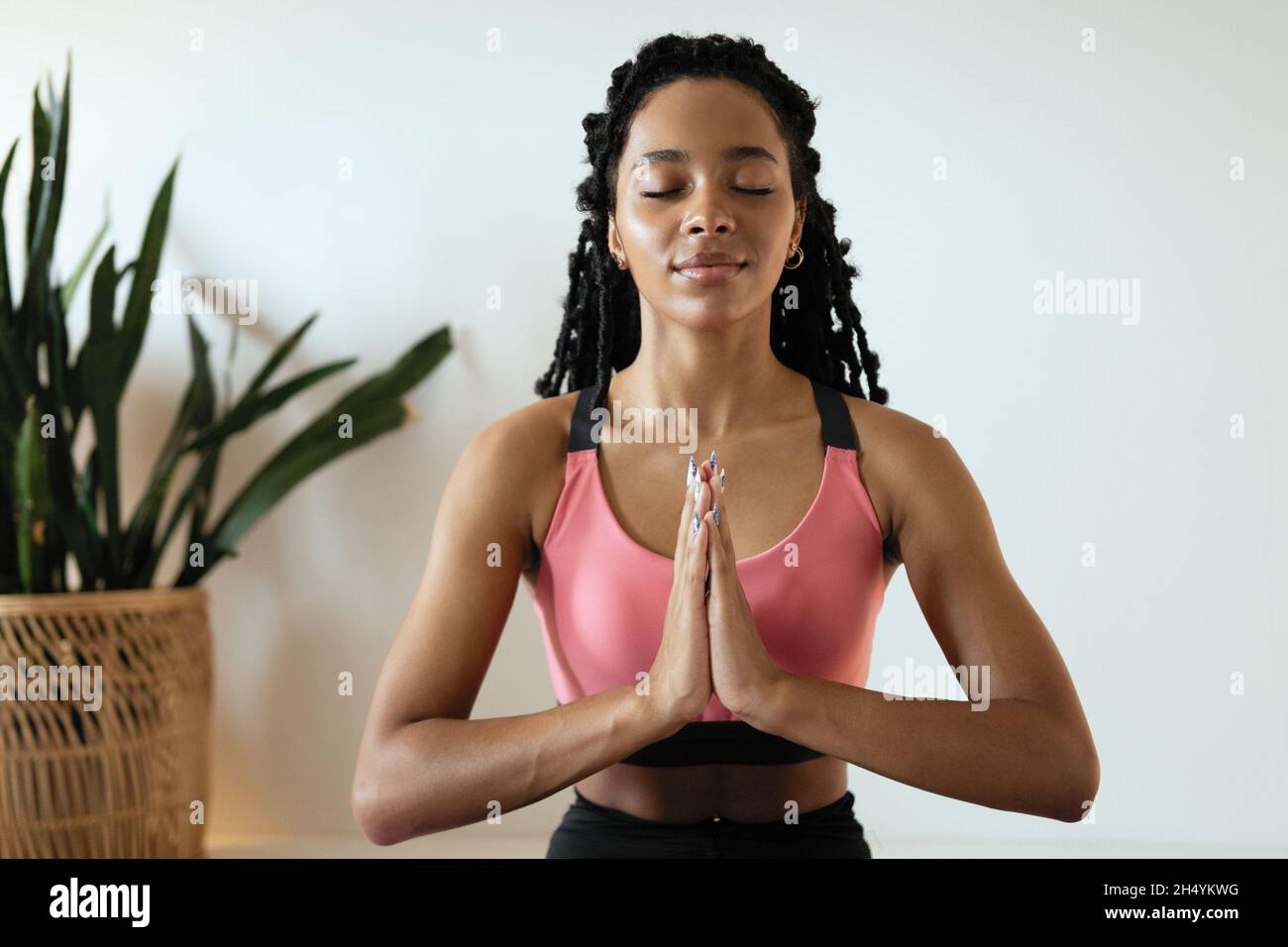 Junge schwarze Frau beim Yoga zu Hause im Lotussitz Stockfoto