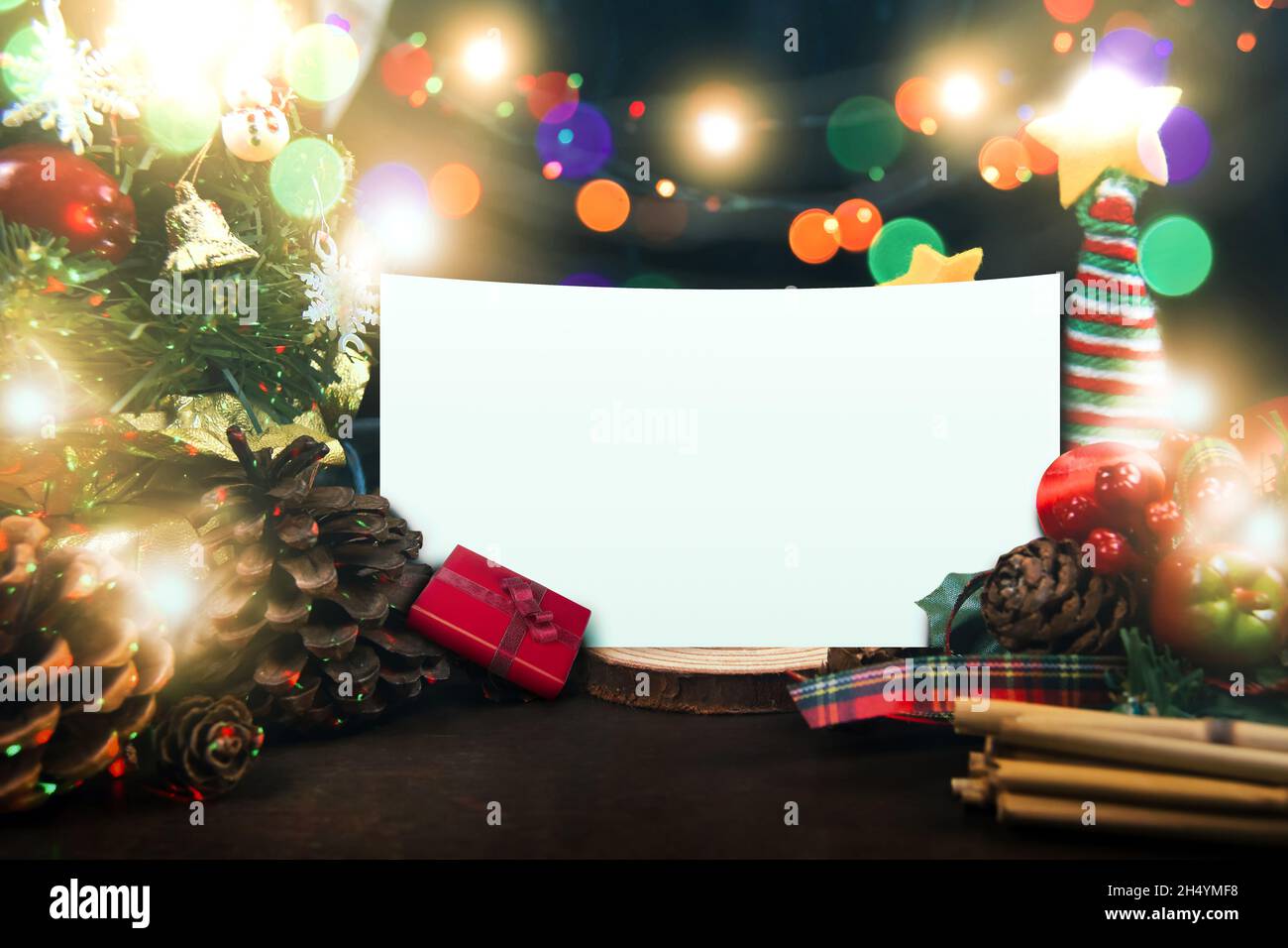 Frohe Weihnachten und ein Happy New Year Konzept, mit einem dekorierten Ornament, einer Geschenkbox, einem Weihnachtsbaum, Tannenzapfen, Beleuchtung und weißem Papierkopierraum Stockfoto