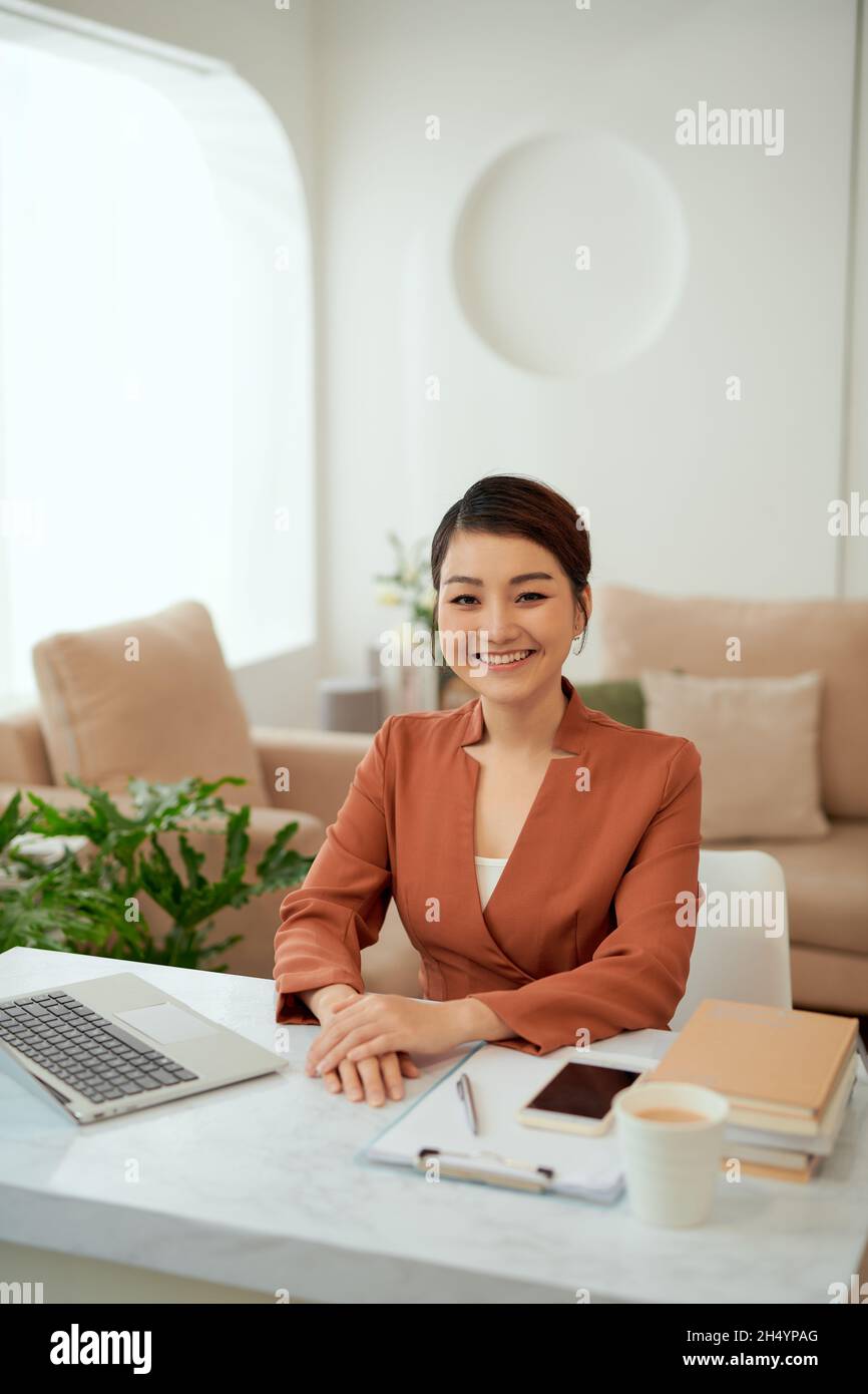 Asiatische Frau, die im Heimbüro mit einem Laptop arbeitet. Stockfoto