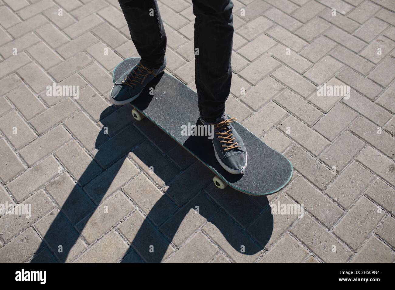 Niedriger Abschnitt des Mannes balanciert auf Skateboard an der Promenade während des sonnigen Tages Stockfoto