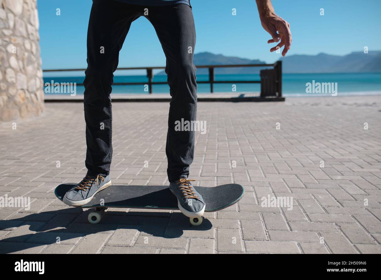 Niedriger Abschnitt des Mannes Skateboarding auf Promenade gegen den Himmel während des sonnigen Tages Stockfoto