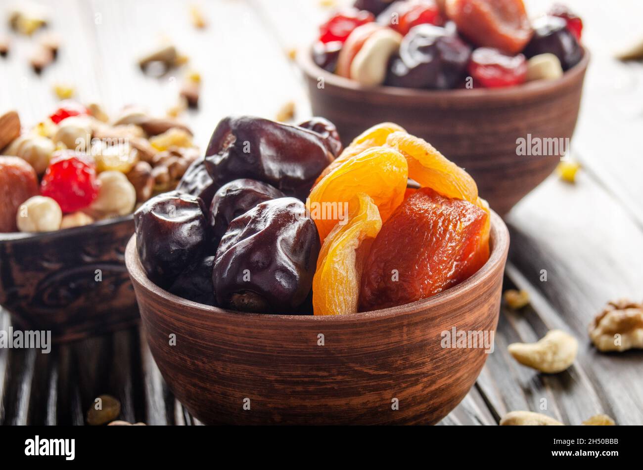 Getrocknete Datteln und Aprikosen in Tonschüssel auf Holzküche Nahaufnahme des Tisches Stockfoto