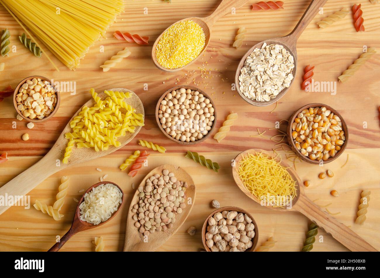 Flat Lay Food Hintergrund aus Hülsenfrüchten Getreide Nudeln und Körner in Holzlöffeln auf Küchentisch Stockfoto