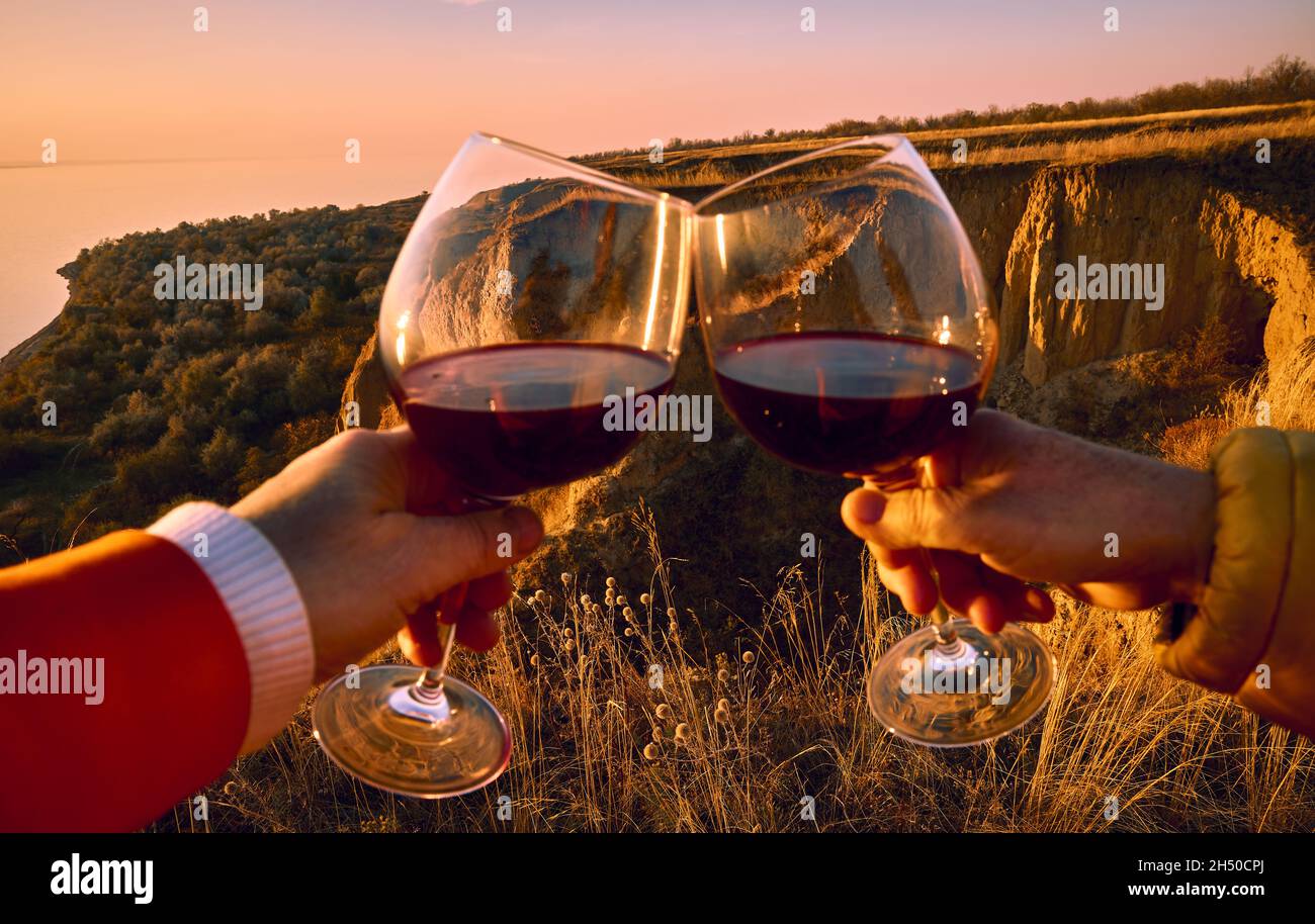 Zwei Gläser mit Rotwein in ausgestreckten Händen und Belgorod Dnestrovsky Canyon im Hintergrund Stockfoto