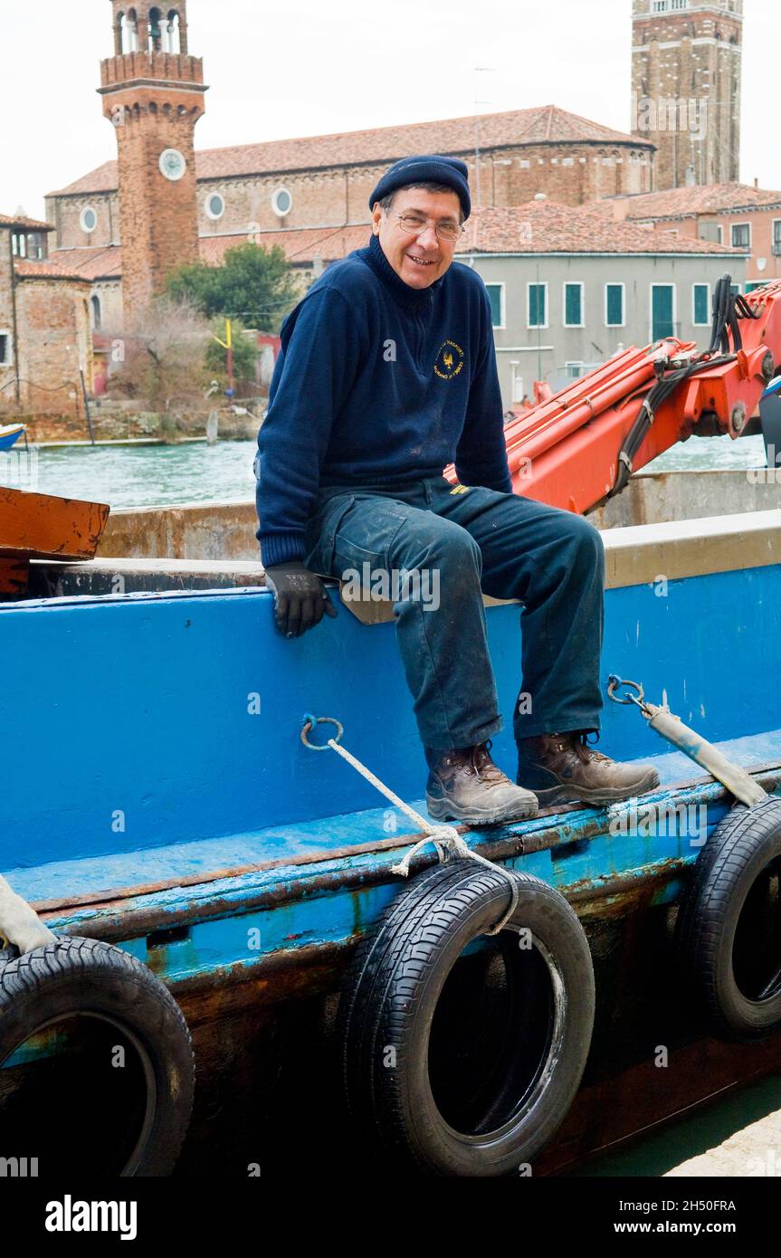 Eine venezianische Mann sitzt auf der Seite eines blauen Boot Stockfoto