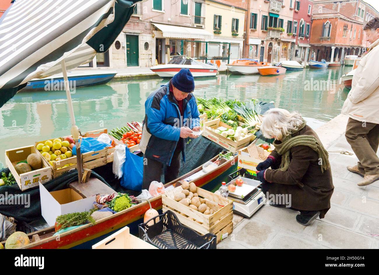 Ein Bootsladen an einem venezianischen Kanal, der Obst und Gemüse verkauft frisch gepflückte Äpfel. Stockfoto