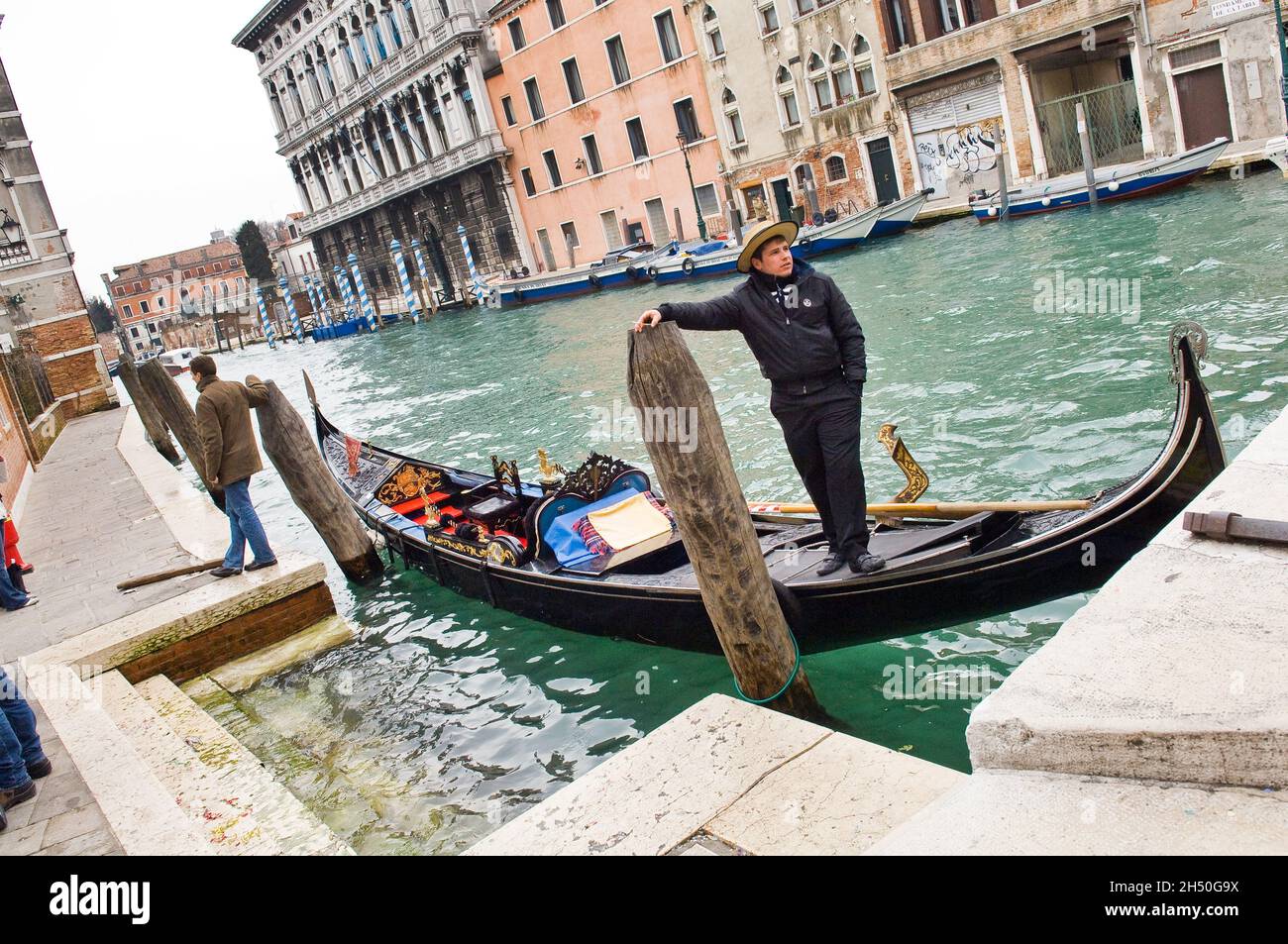 Ein gondoliere Lenkung eine Gondel unter anderem Boote einschließlich der Fluss Bushaltestelle in Venedig, Italien, in der Nähe des Bahnhofs. Stockfoto