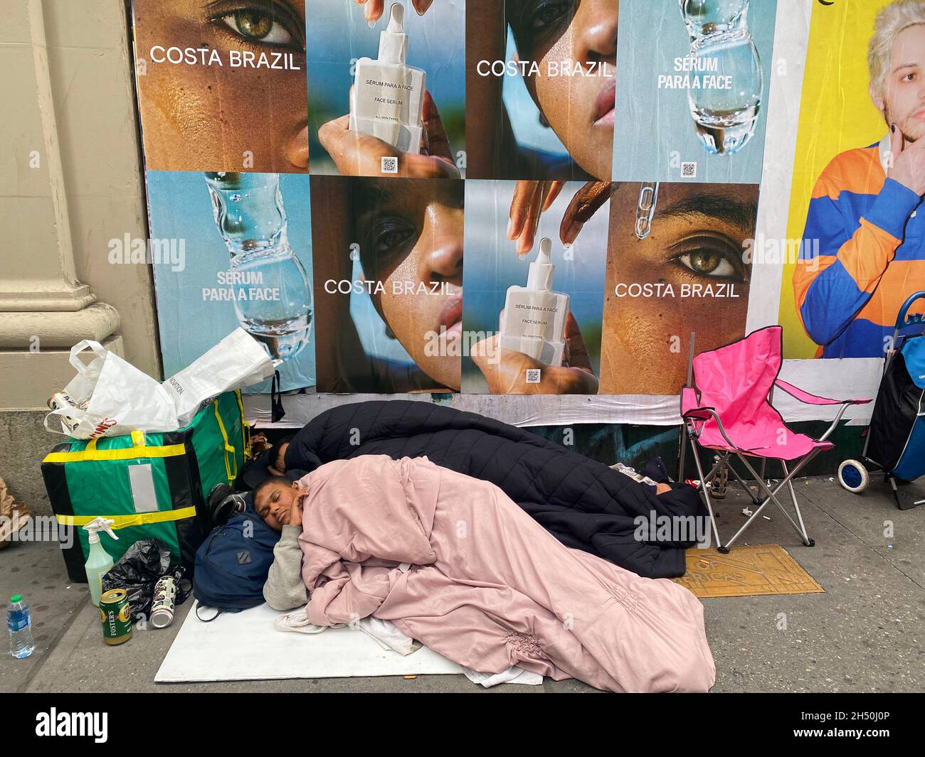 Zwei Obdachlose schlafen am Nachmittag in New York City an der 6th Avenue in der Midtown Manhattran. Stockfoto