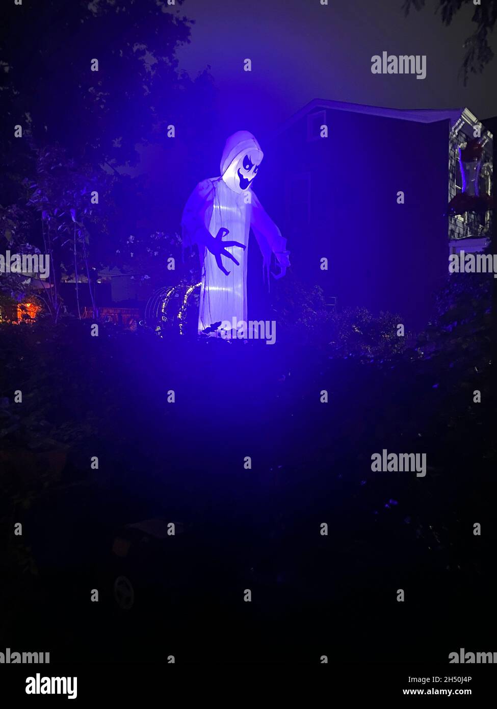 An Halloween im Wohnviertel von Kensington in Brooklyn, New York, ragt ein riesiger Geist in einem Vorgarten auf. Stockfoto