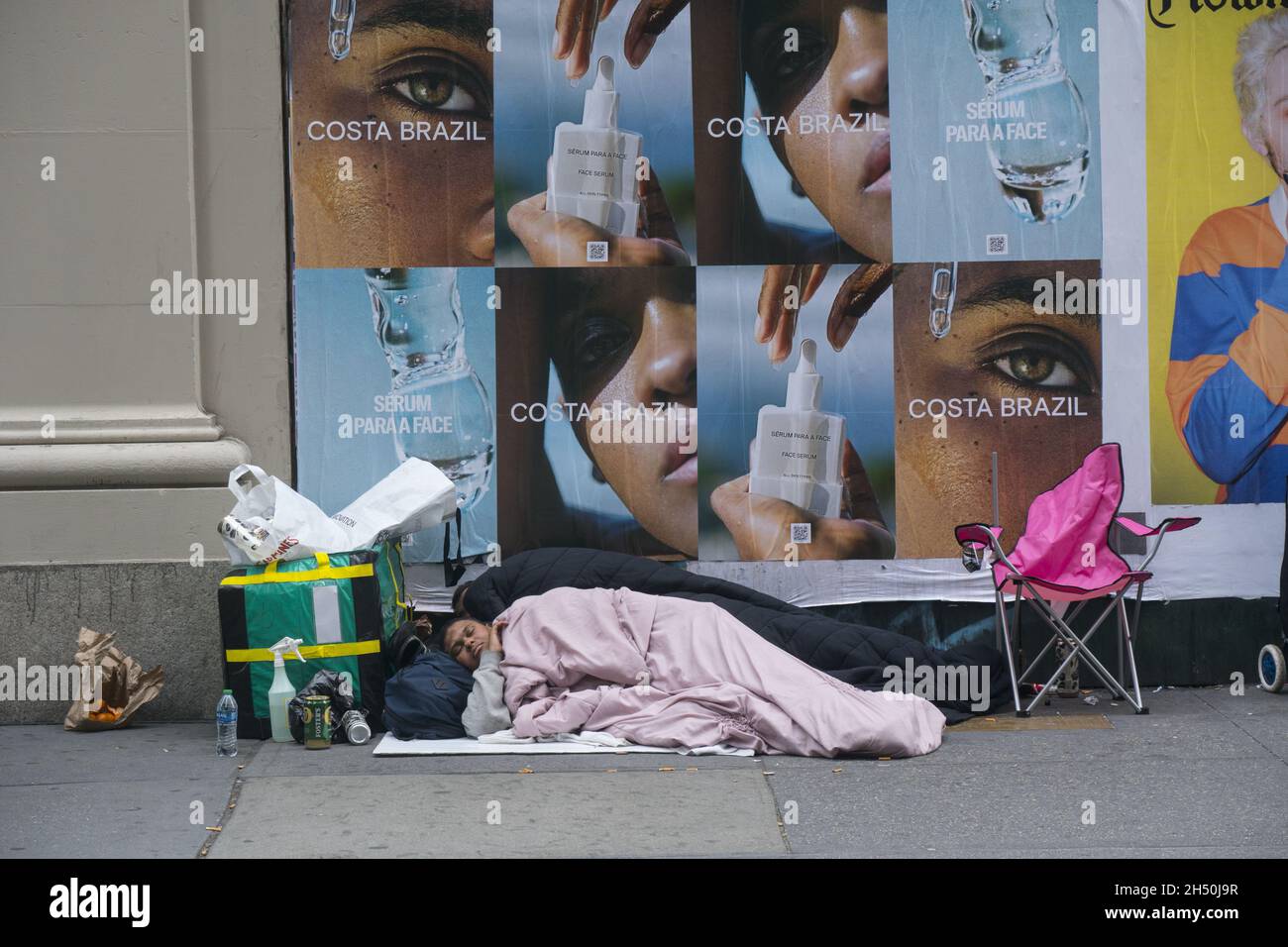 Zwei Obdachlose schlafen am Nachmittag in New York City an der 6th Avenue in Midtown Manhattan. Stockfoto