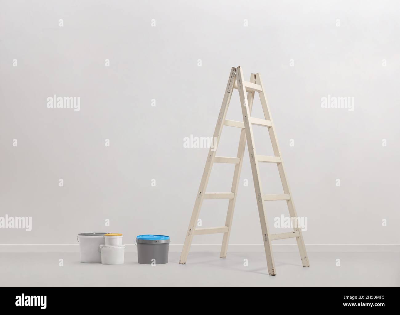 Malvorräte und eine weiße Leiter vor einer Wand Stockfoto