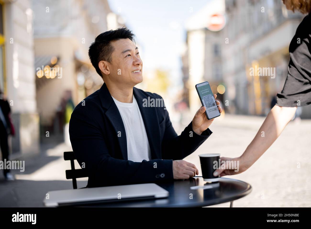 Mann zeigen Telefon mit Impfanwendung im Café Stockfoto