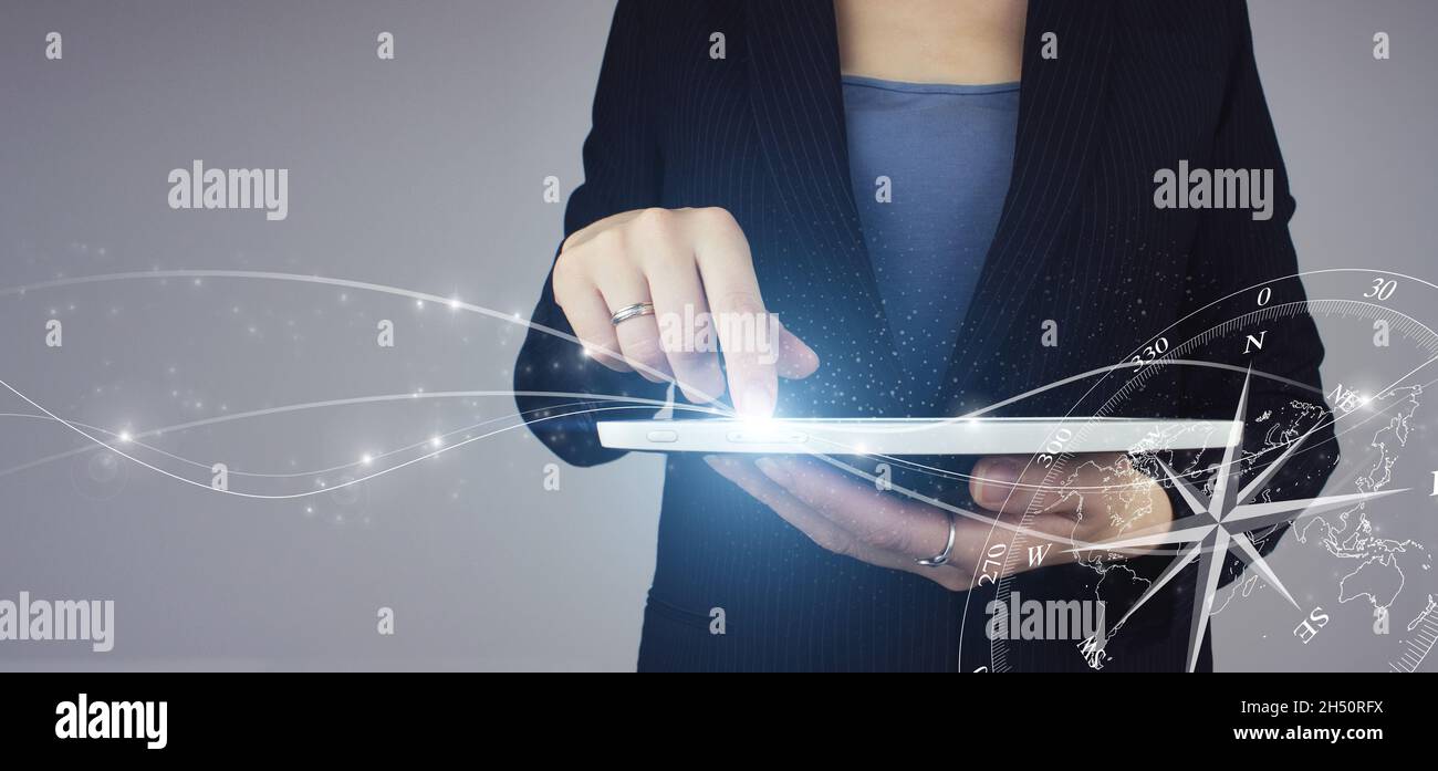 Business Navigate Recovery. Weiße Tablette in Geschäftsfrau Hand mit digitalem Hologramm Kompass Zeichen auf grauem Hintergrund. Der Kompass navigiert für Geschäftsleute Stockfoto