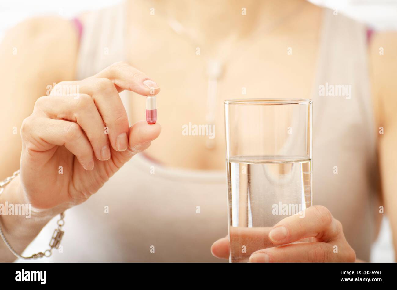 Kaukasische weibliche Model hält Pille und Glas Wasser in der Nähe in den Händen Stockfoto