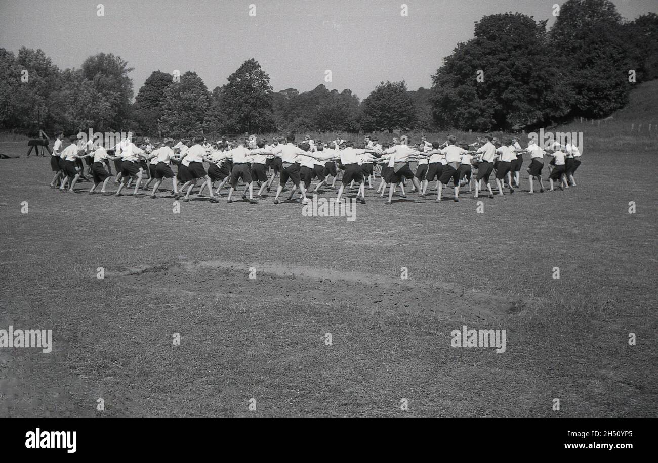 1950, historisch, draußen auf einem Sport- oder Spielfeld, eine große Gruppe von Schülern, die an einer Sportklasse teilnehmen, England, Großbritannien. Ein Knauf oder ein vaulting Pferd, ein Stück Turnausrüstung kann gesehen werden. Stockfoto