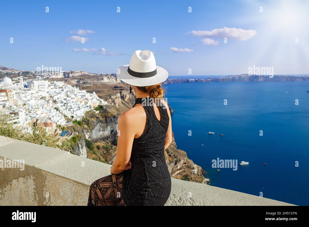 Frau in einem schwarzen Kleid auf der Terrasse blickt auf das Meer, Griechenland, Santorini Stockfoto