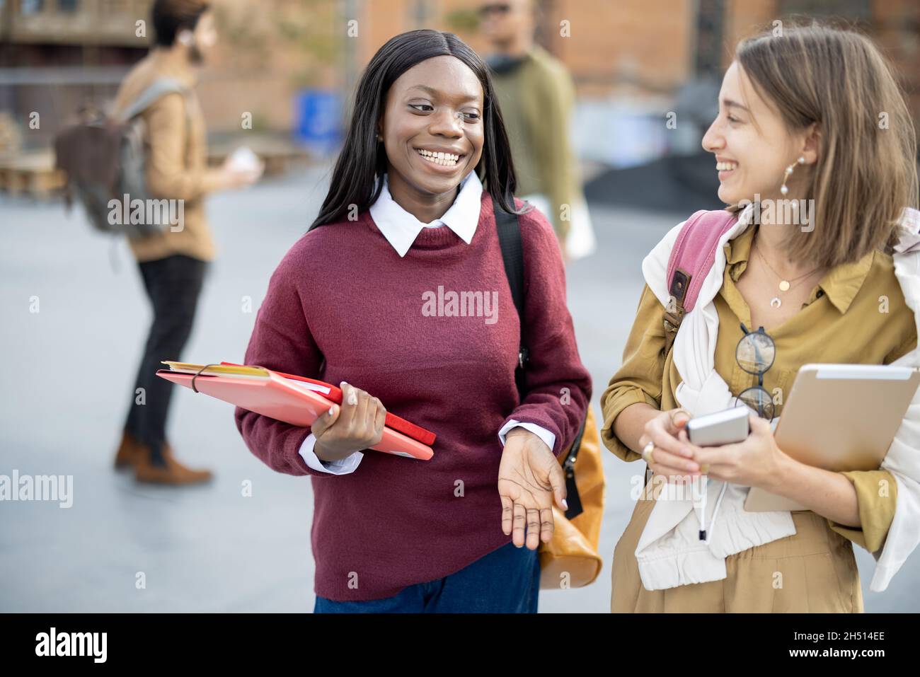 Studentinnen mit Büchern, die gehen und sprechen Stockfoto